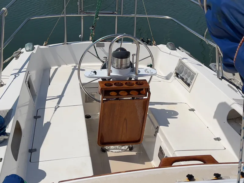 Slide: The Image of Cockpit of a 1986 Catalina 30 sailboat with steering wheel and wooden table. - 8