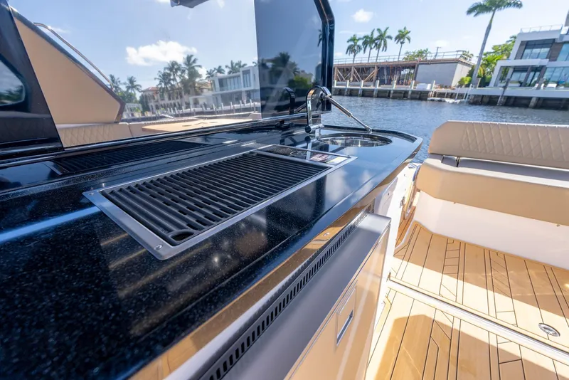 Slide: The Image of Outdoor kitchen on 2025 Hanover 347 Outboard boat with grill and sink, docked by waterfront homes. - 10
