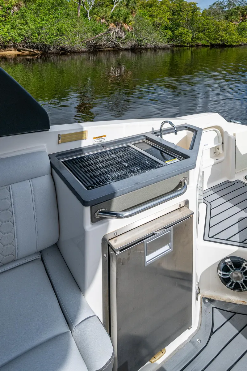 Slide: The Image of 2022 Sea Ray SDX 290 boat interior with grill and seating by the water. - 22