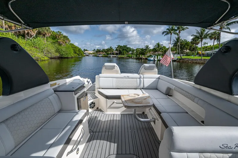 Slide: The Image of 2022 Sea Ray SDX 290 boat interior with seating, table, and scenic waterway view. - 23