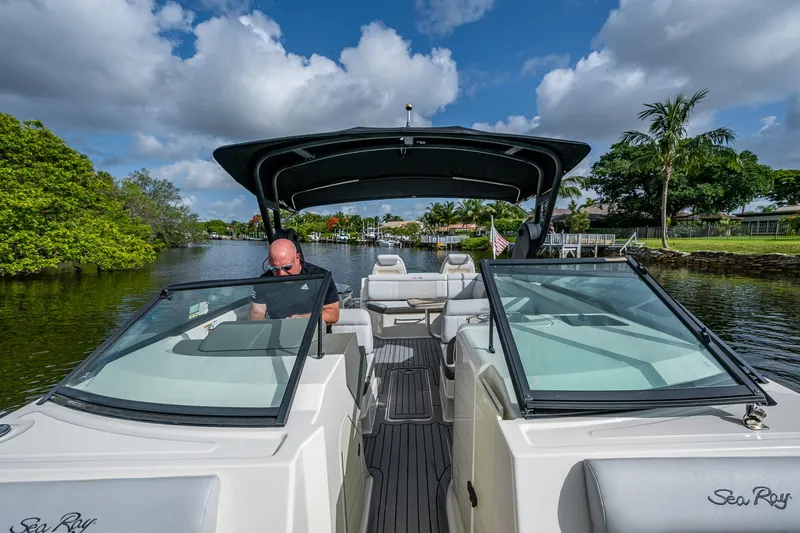 Slide: The Image of 2022 Sea Ray SDX 290 boat cruising on a scenic waterway under a clear blue sky. - 27