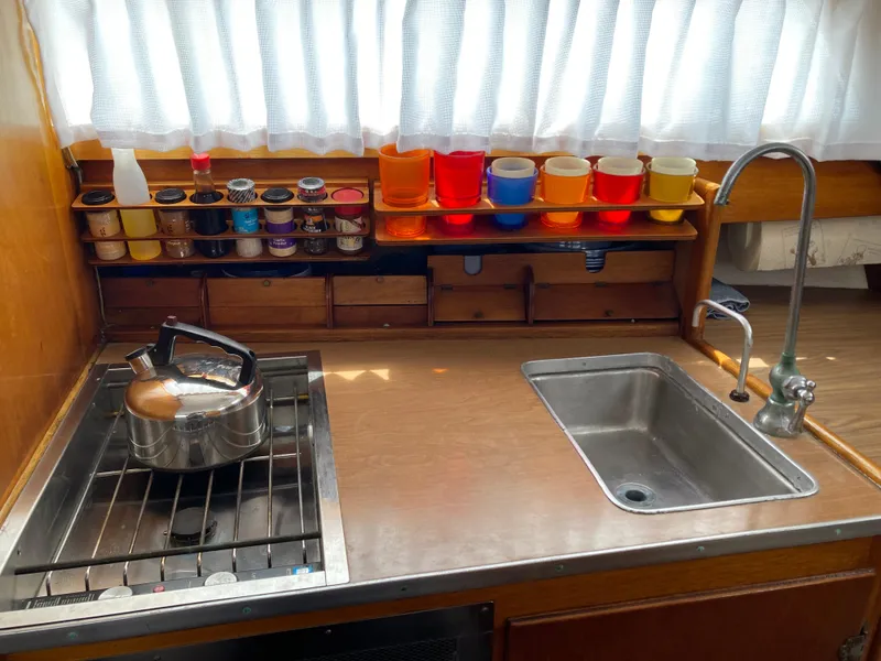 Slide: The Image of Compact kitchen area in a 1963 Sumnercraft 31 Motor Sailer with stove, sink, and colorful containers. - 17