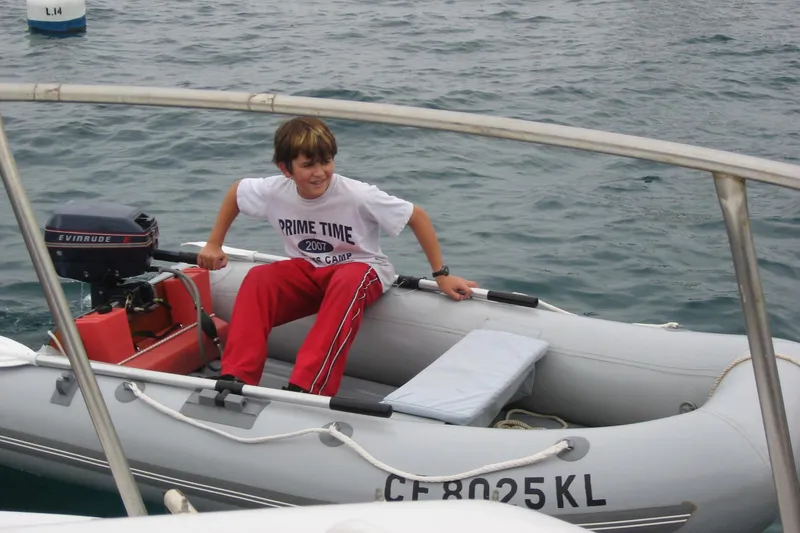 Slide: The Image of Young person in a small inflatable boat on water, near a 1963 Sumnercraft 31 Motor Sailer. - 33