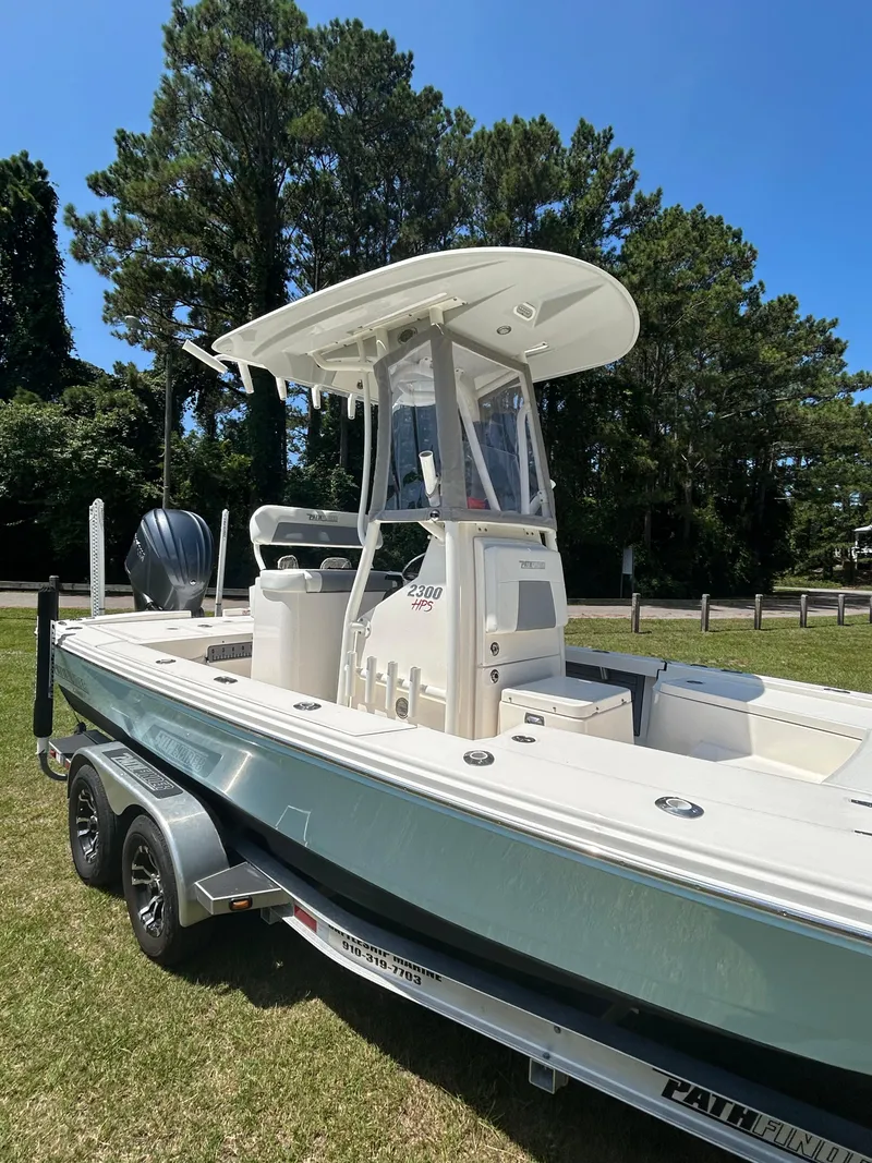 Slide: The Image of 2023 Pathfinder 2300 HPS boat on trailer, parked on grass with trees in background. - 39