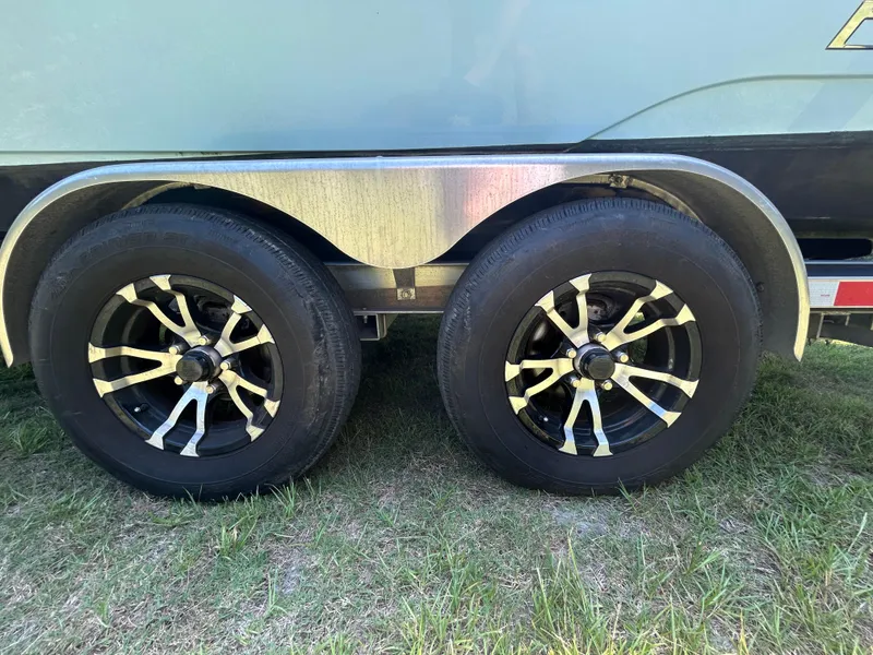 Slide: The Image of 2023 Pathfinder 2300 HPS boat interior with center console and seating, parked on grass. - 47