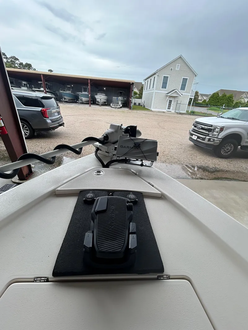 Slide: The Image of 2023 Pathfinder 2300 HPS boat with open storage compartments, parked near vehicles and buildings. - 6