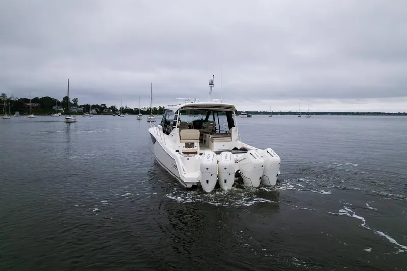 Slide: The Image of 2024 Boston Whaler 405 Conquest boat on calm water, rear view with multiple outboard engines. - 11