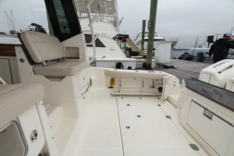 Slide: The Image of 2024 Boston Whaler 405 Conquest boat interior with seating and storage, docked at marina. - 24