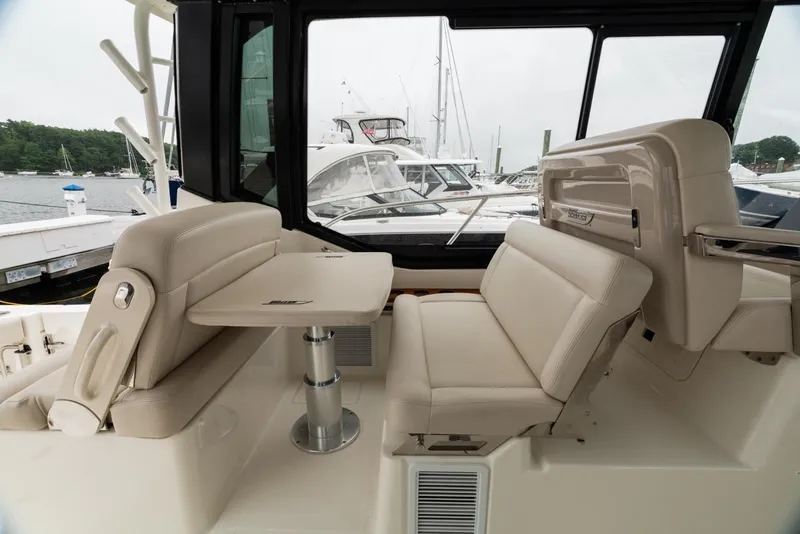 Slide: The Image of 2024 Boston Whaler 405 Conquest interior seating area with table, docked at marina. - 31