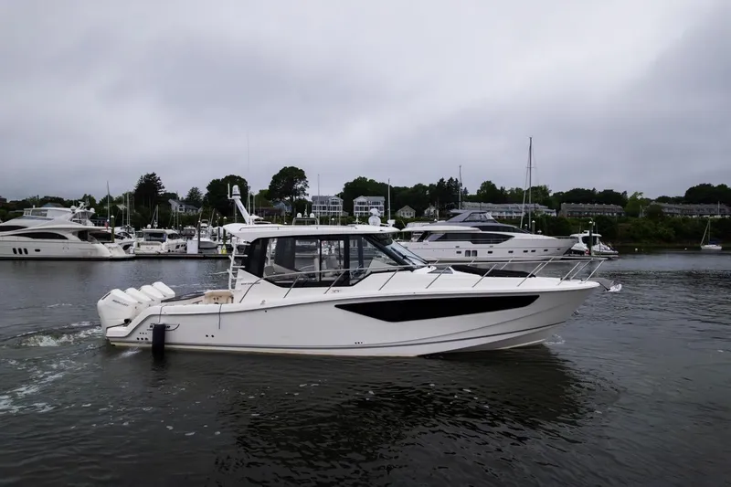 Slide: The Image of 2024 Boston Whaler 405 Conquest cruising in a marina with other yachts. - 4