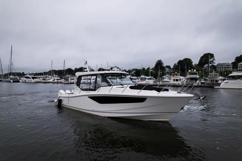 Slide: The Image of 2024 Boston Whaler 405 Conquest boat docked in a marina, surrounded by other vessels. - 5