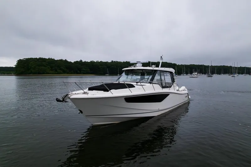 Slide: The Image of 2024 Boston Whaler 405 Conquest boat on calm water, overcast sky, forested shoreline. - 7