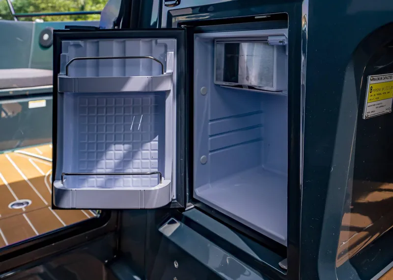 Slide: The Image of Open fridge on 2023 XO Boats EXPLR 9, showcasing interior storage space. - 29