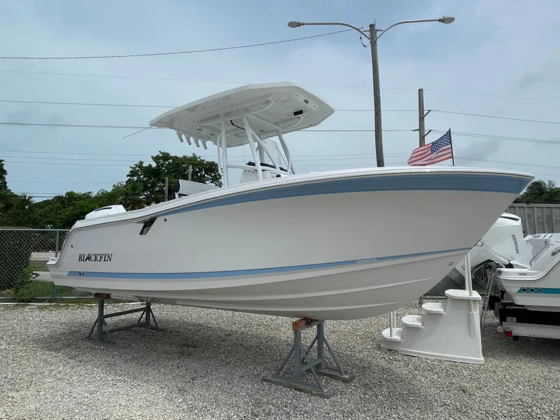 Slide: The Image of 2026 Blackfin 222CC boat on display, white hull, blue stripe, American flag in background. - 1