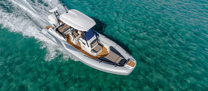 The Image of 2025 Grand Inflatables G750 boat cruising on clear turquoise water. - 1
