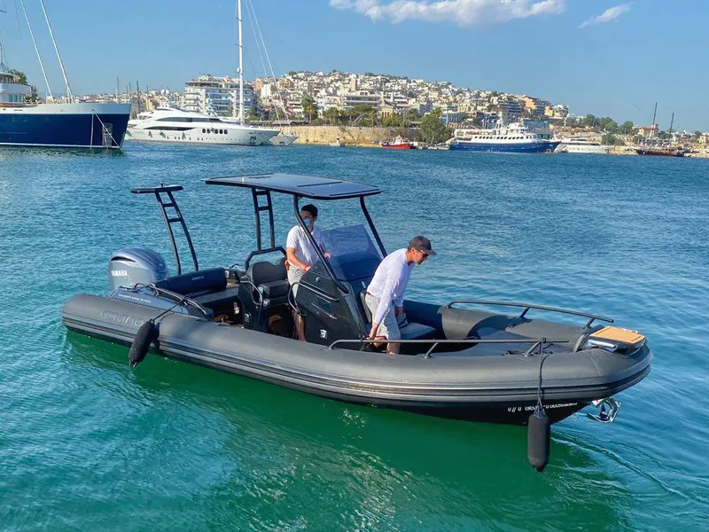 Slide: The Image of 2025 Grand Inflatables G750 boat on clear blue water, with two people onboard. - 12
