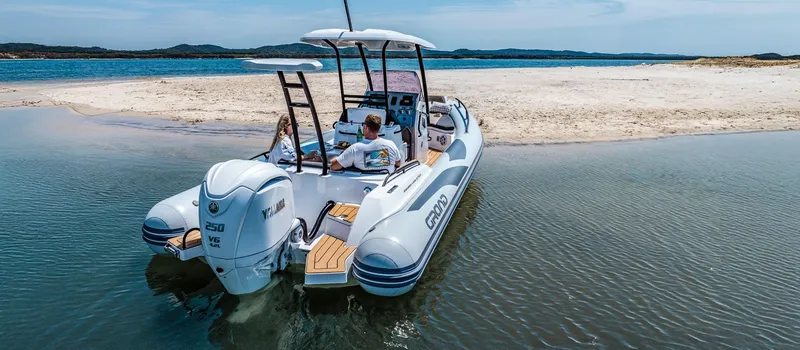 Slide: The Image of 2025 Grand Inflatables G750 boat docked on a sandy beach, featuring twin engines. - 3