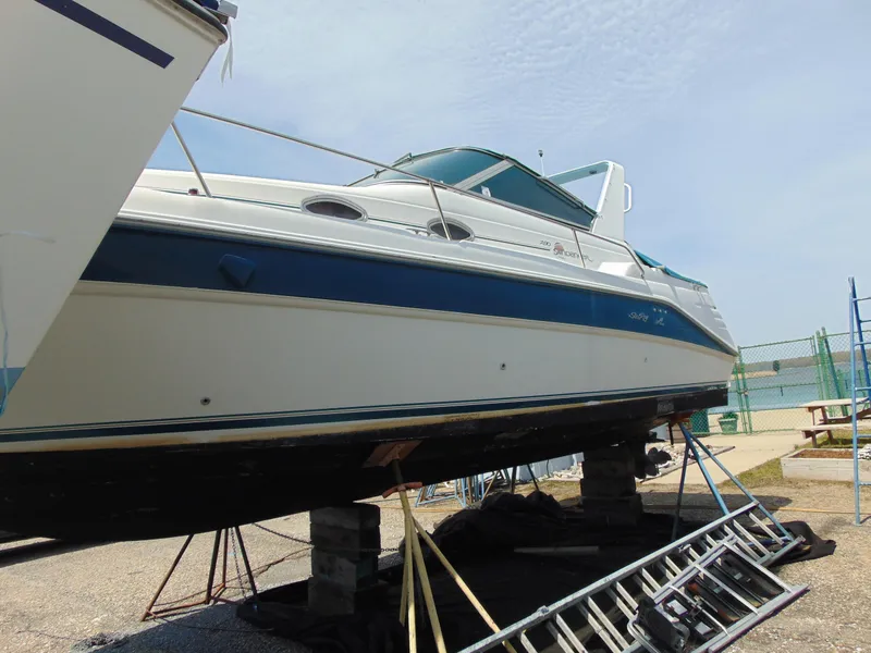 Slide: The Image of 1996 Sea Ray 290 boat on dry dock, blue and white hull, outdoor setting. - 2