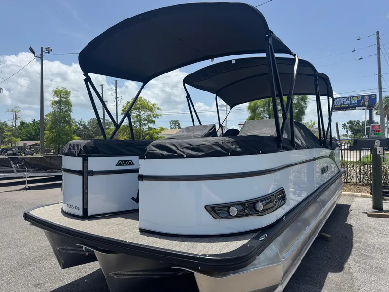 Slide: The Image of 2025 Avalon Catalina Platinum Quad Lounge 25' pontoon boat with black canopy, parked outdoors. - 11