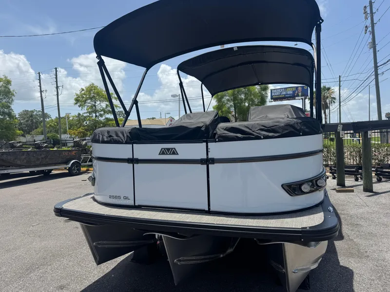 Slide: The Image of 2025 Avalon Catalina Platinum Quad Lounge boat, rear view, parked outdoors under a clear sky. - 12