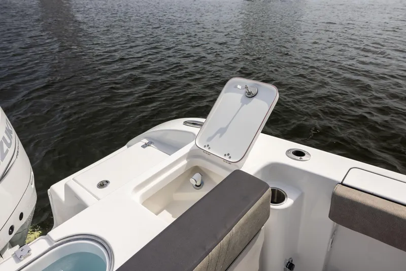 Slide: The Image of 2025 Sea Pro 240 Dual Console boat with open storage compartment on calm water. - 10