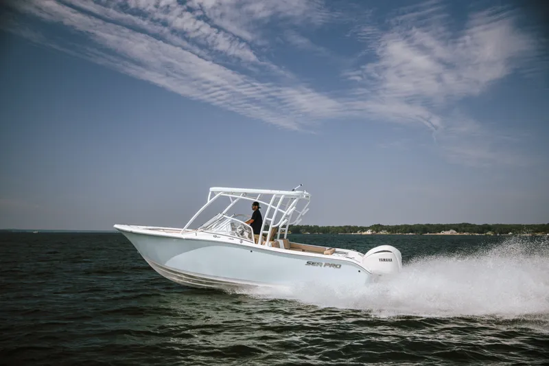 Slide: The Image of 2025 Sea Pro 240 Dual Console boat cruising on open water under a clear sky. - 13