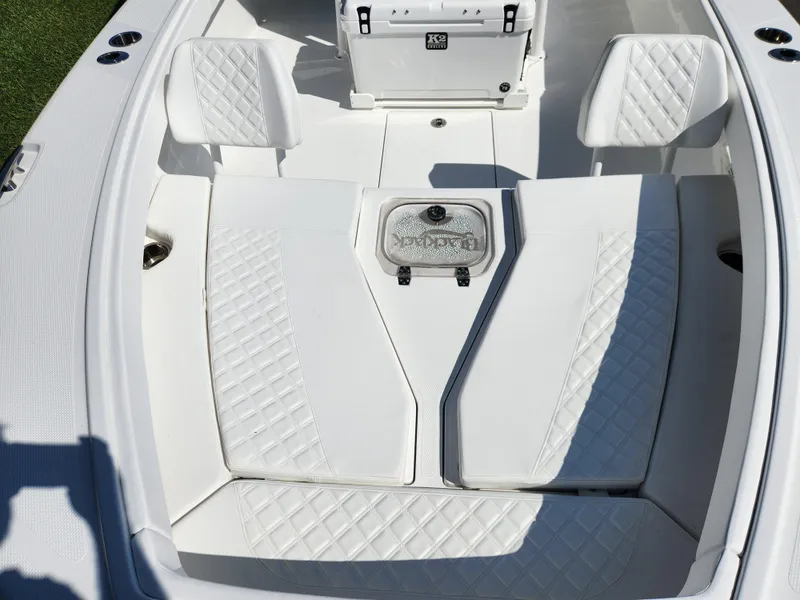 Slide: The Image of 2025 BlackJack 256 Coastal boat interior with white cushioned seating and storage compartment. - 10