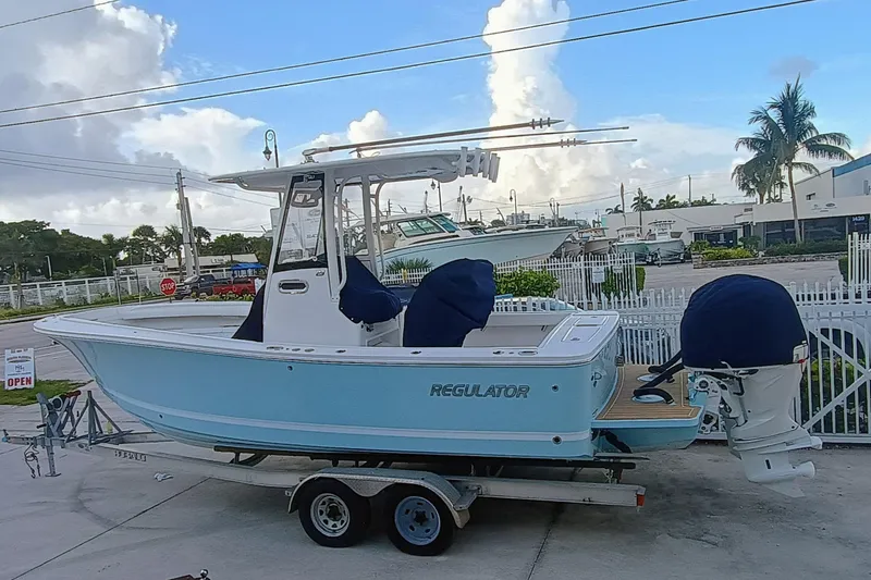 Slide: The Image of 2025 Regulator 23 Center Console boat on trailer, light blue hull, outdoor setting. - 8