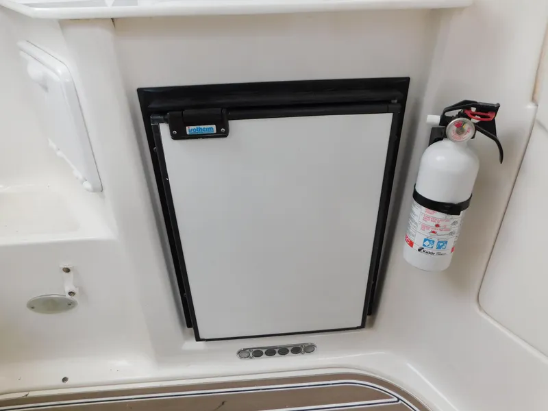 Slide: The Image of 2003 Regal 2860 Commodore boat interior with a compact refrigerator and fire extinguisher. - 12