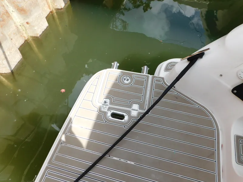Slide: The Image of 2003 Regal 2860 Commodore boat deck near water, featuring sleek design and mooring cleats. - 17