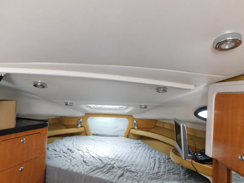 Slide: The Image of 2003 Regal 2860 Commodore cabin interior with bed, wood cabinets, and small TV. - 48