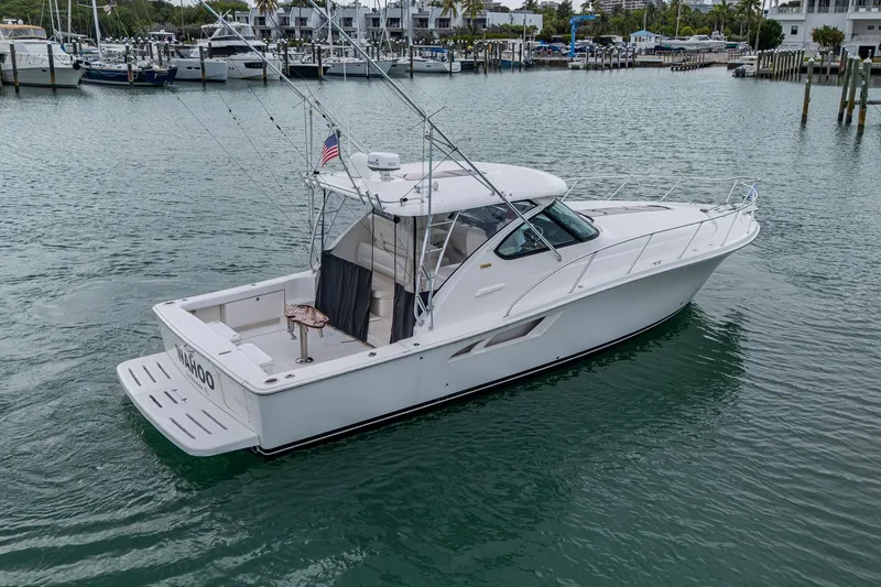 Slide: The Image of 2009 Tiara Yachts 39 Open cruising in a marina, showcasing sleek design and fishing equipment. - 16