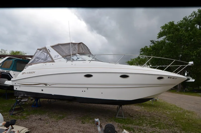 The Image of 2002 Larson 330 Cabrio boat on land, white exterior, overcast sky background. - 1