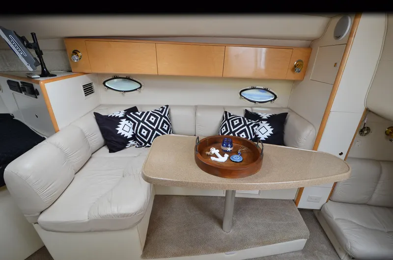 Slide: The Image of 2002 Larson 330 Cabrio cabin interior with seating, table, and decorative pillows. - 10