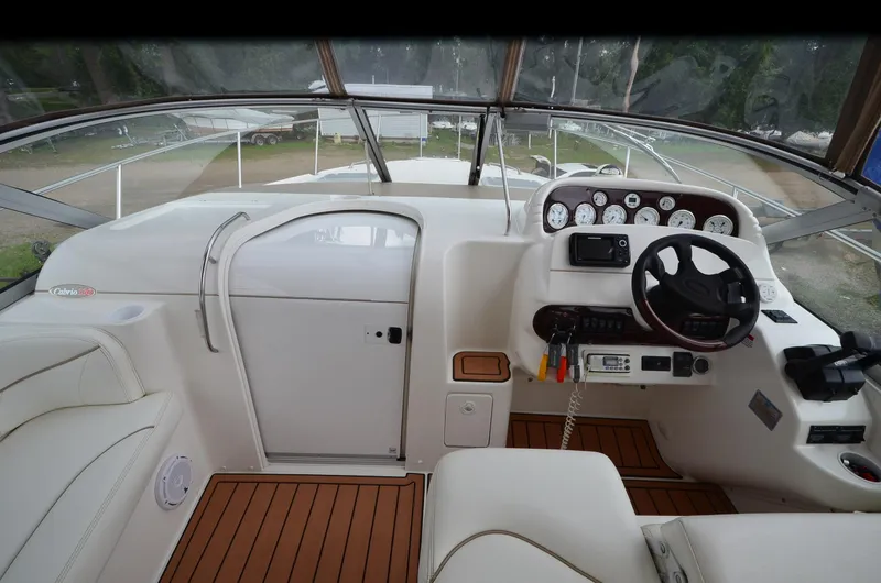 Slide: The Image of 2002 Larson 330 CABRIO boat cockpit with steering wheel, gauges, and wood flooring. - 15