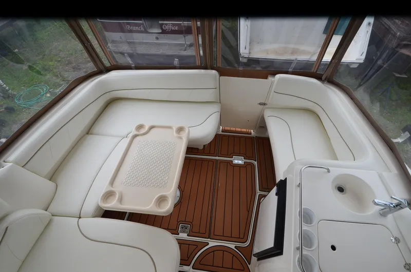 Slide: The Image of 2002 Larson 330 Cabrio boat interior with white seating, wooden flooring, and a small sink. - 16
