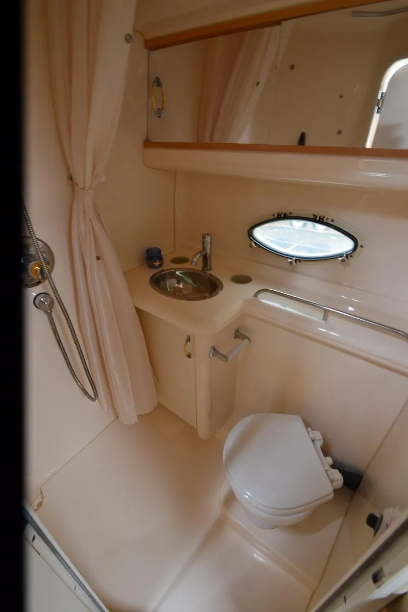 Slide: The Image of 2002 Larson 330 CABRIO boat bathroom with sink, toilet, and porthole window. - 21