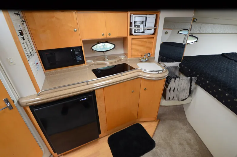 Slide: The Image of 2002 Larson 330 CABRIO interior with kitchenette, featuring wood cabinets, microwave, and compact fridge. - 4