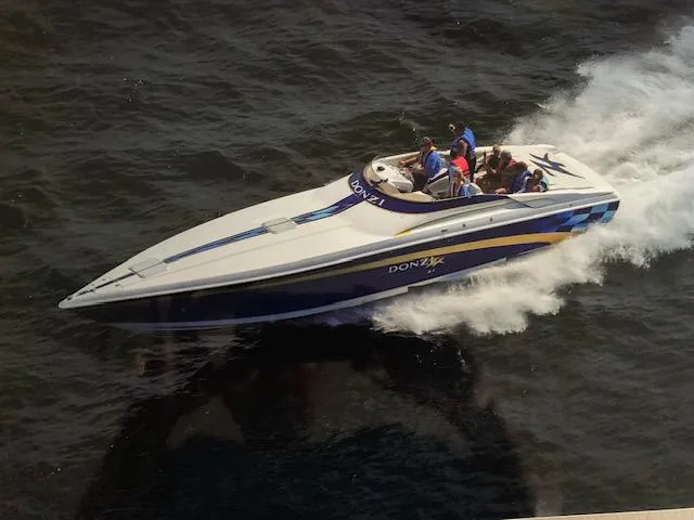 The Image of 2000 Donzi 38 ZX speedboat cruising on open water with passengers. - 1