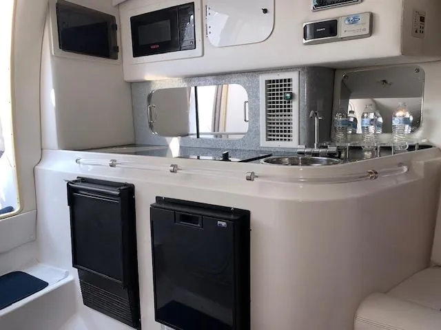 Slide: The Image of Interior of 2000 Donzi 38 ZX boat featuring kitchenette with appliances and water bottles. - 11