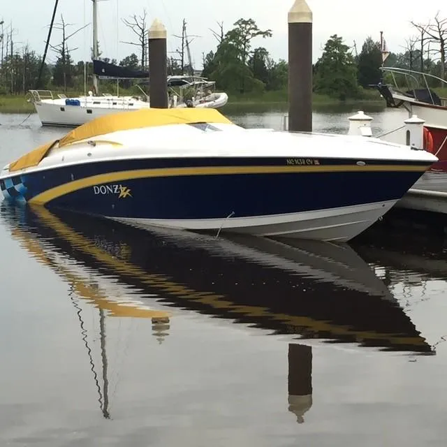 Slide: The Image of 2000 Donzi 38 ZX speedboat with yellow cover docked in a marina. - 15
