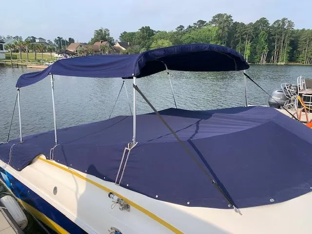 Slide: The Image of 2000 Donzi 38 ZX boat with blue canopy, docked by a serene lake. - 16