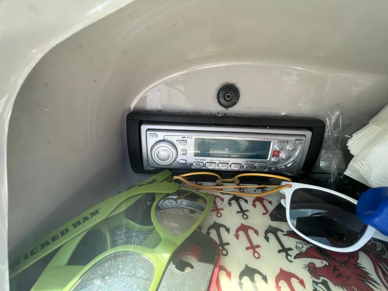 Slide: The Image of Boat dashboard with stereo, sunglasses, and anchor-patterned fabric in a 2005 Chaparral 236SSi. - 18