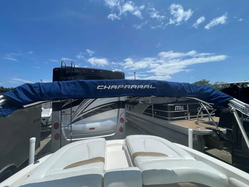 Slide: The Image of 2005 Chaparral 236SSi boat with blue cover, parked under a clear blue sky. - 21