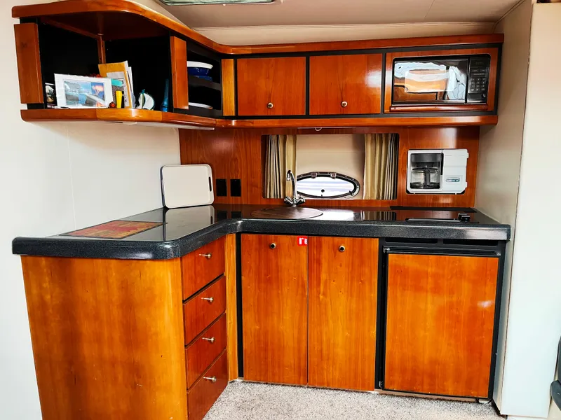Slide: The Image of Trojan 400 Express Yacht 2000 kitchen with wood cabinets, microwave, and compact fridge. - 6