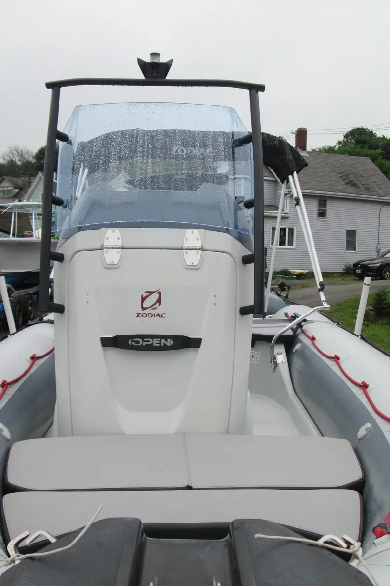 Slide: The Image of 2020 Zodiac Open 5.5 boat with windshield, docked near residential area. - 5