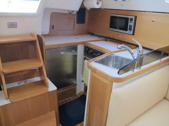 Slide: The Image of 2015 Catalina 315 yacht interior kitchen with sink, microwave, and wooden cabinetry. - 3