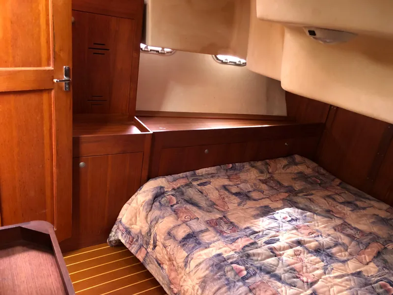 Slide: The Image of Cozy cabin interior of 2000 Hunter 410 sailboat with wooden furnishings and patterned bedding. - 12