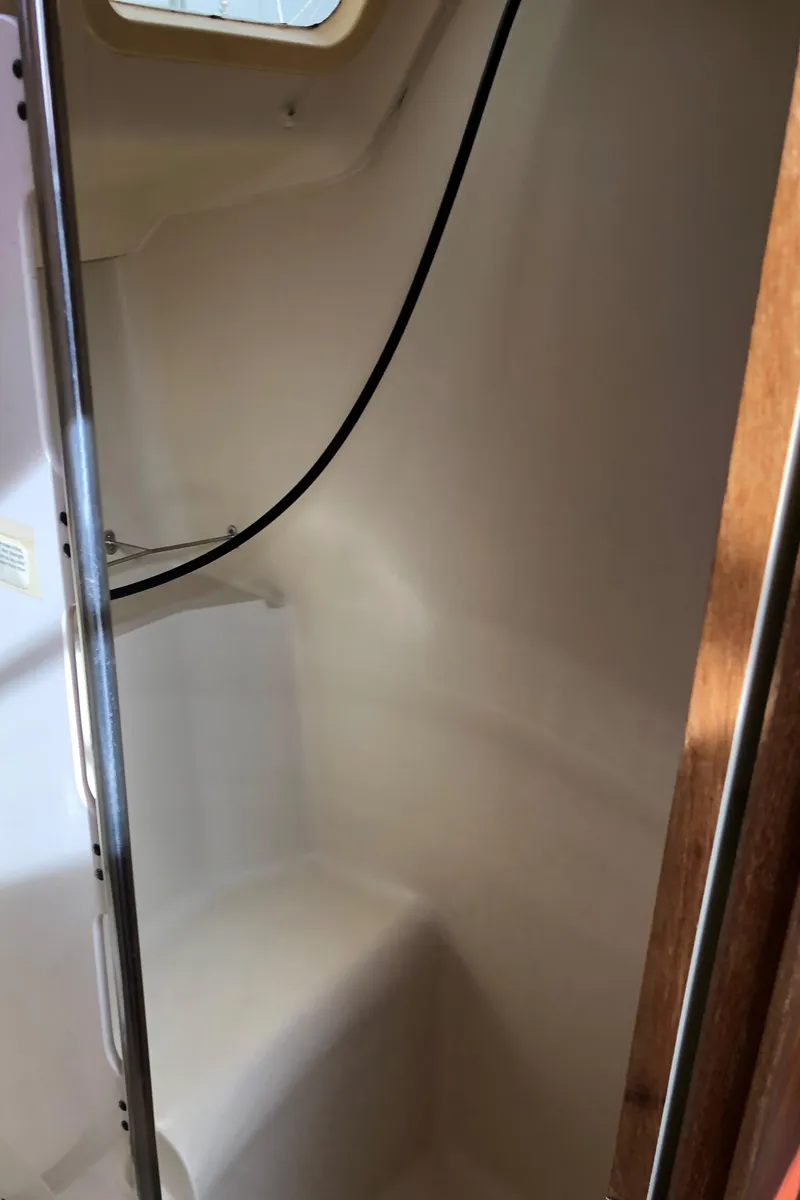 Slide: The Image of Interior of a 2000 Hunter 410 sailboat shower area with white walls and a window. - 30