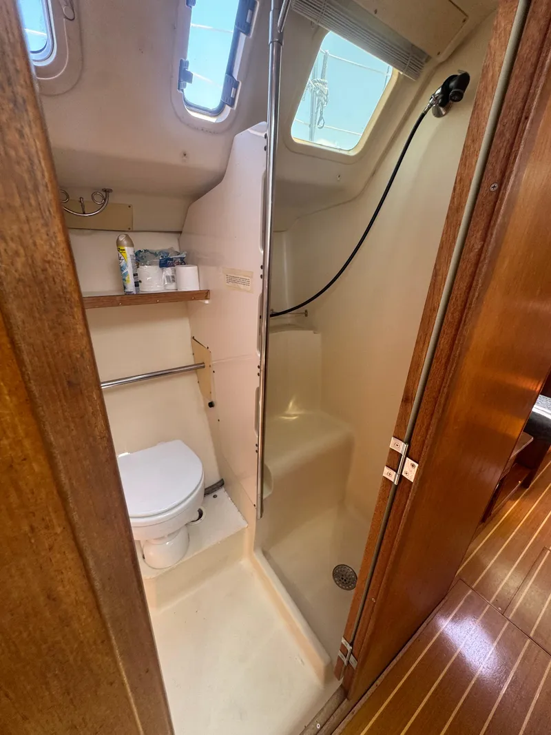Slide: The Image of Compact bathroom in a 2000 Hunter 410 sailboat with toilet, shower, and wooden accents. - 45